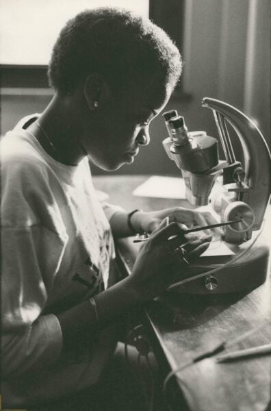Mundelein student Laura Innis utilizing a microscope for an assignment in the biology lab. 1982. 