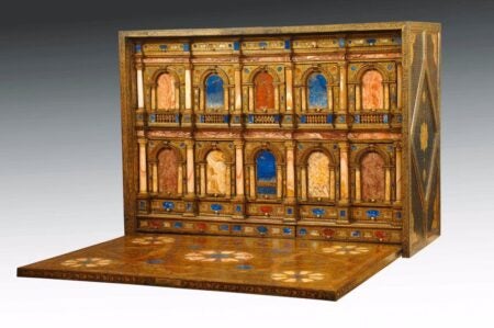 Ornate Renaissance writing desk or kabinettschrank from Venice, second half of the 16th century, featuring intricate architectural detailing with arches, columns, and inlaid semiprecious stones in vibrant hues of blue, red, and gold. The open structure reveals a fold-out surface with elaborate patterns and decorative craftsmanship.